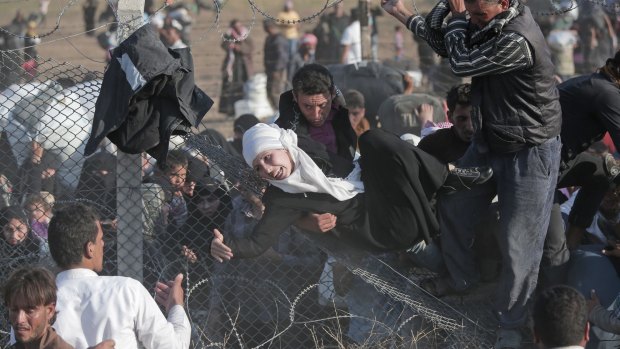 Desperate Syrian refugees scale the border fence at Akcakale.