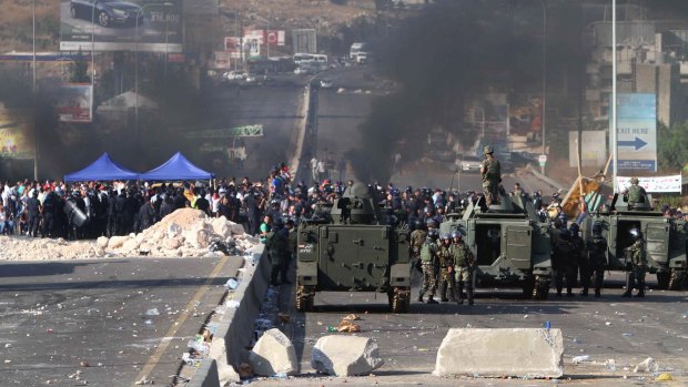 Lebanese army soldiers stand next of their armoured personnel carriers as they prepare to reopen a highway linking Beirut to southern Lebanon blocked by angry protesters, in the coastal town of Jiyeh on Monday.