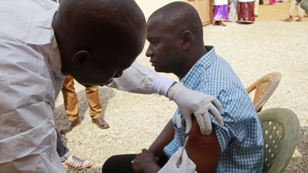 A health worker injects a man with an experimental Ebola vaccine in Guinea in March 2015. 