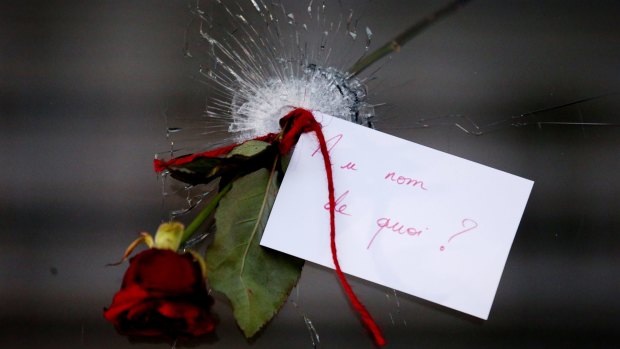 A rose in a bullet hole with a note that translates to "In the name of what?" at La Belle Equipe in Paris on Sunday.