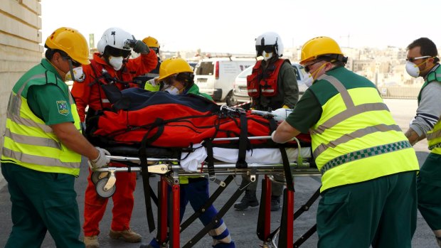 Paramedics prepare to lift an ill migrant on a stretcher into a waiting ambulance after she arrived by an Italian military helicopter at St Luke's Hospital in Gwardamangia, Malta.