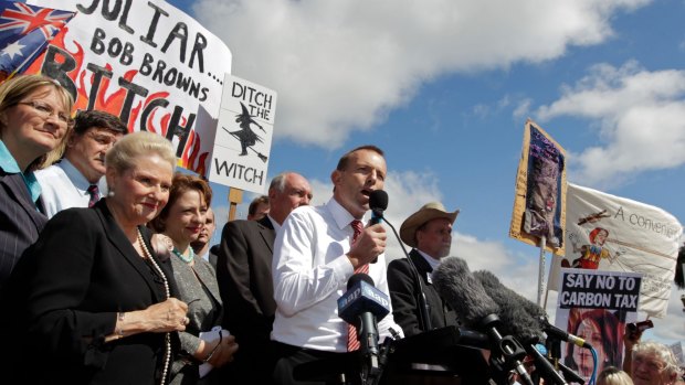 Tony Abbott as opposition leader in front of posters at a ant-carbon tax rally.