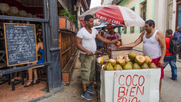 Street vendor sells fresh chilled coconuts on the busy pedestrian street Obispo in the historic La Habana Vieja neighbourhood. 