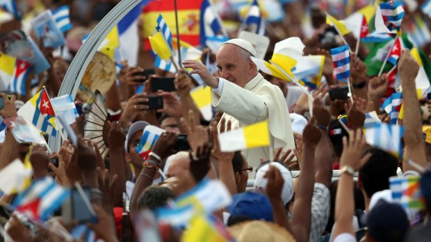 People wave Cuban and Papal flags as Pope Francis arrives to celebrate Mass on September 20,  in Revolution Square in Havana, Cuba.