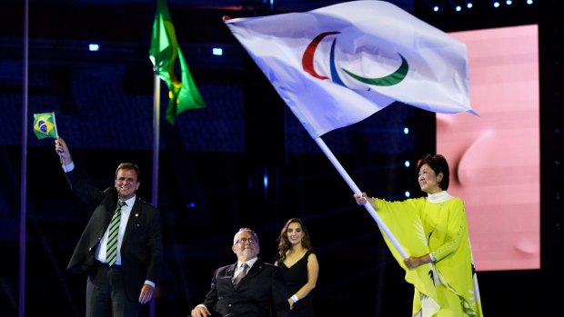 Rio de Janeiro Mayor Eduardo Paes, left, waves as Sir Philip Craven, centre, president of the IPC hands the Paralympic flag to the Governor of Tokyo Yuriko Koike, at the closing ceremony of the Rio 2016 Paralympic Games.