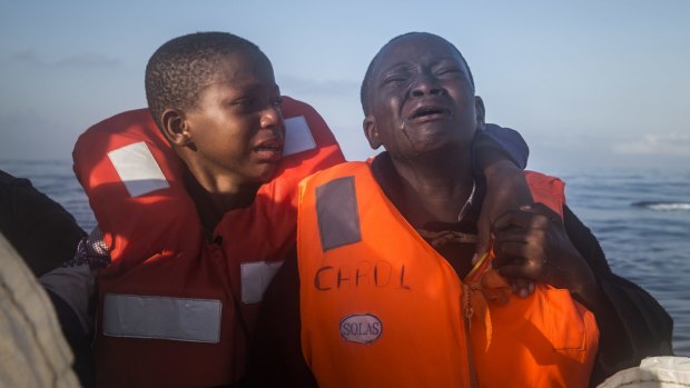 Dustin, right, 11, from Nigeria, who said her mother died in Libya, cries next to her 10-year-old brother, as they board an overcrowded rubber boat and wait to be assisted during a rescue operation on the Mediterranean Sea, north of Sabratha, Lybia, on Thursday.