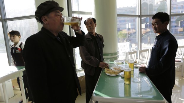 Down time: Pak Sun Won, 66, left, a retired physician with his friends at the stand-up Taedonggang Beer shop.