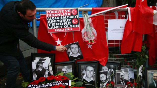 A man adjusts a victim's photograph displayed with floral tributes and Turkish flags outside the Reina night club following the New Year's Day attack in Istanbul.