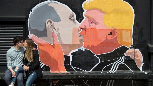 A couple kisses in front of graffiti depicting Vladimir Putin, left, and Donald Trump, on the walls of a bar in the old town in Vilnius, Lithuania, in May.