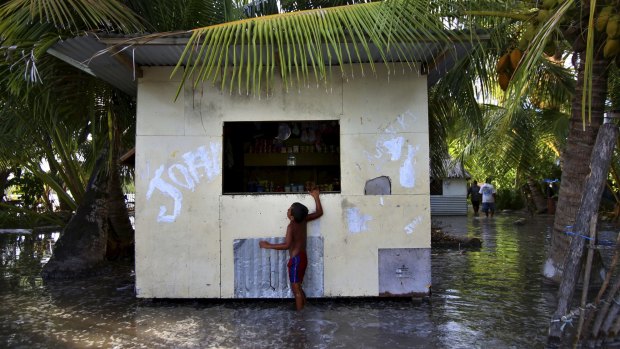  A child wades through sludge and water on the Island Republic of Kiribati in the Central Pacific Ocean.