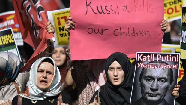 Demonstrators hold placards and a picture depicting Russian President Vladimir Putin during a protest against Russian military operations in Syria, in Istanbul on Saturday. The picture reads both in Turkish and Russian: 'Murderer Putin'. 