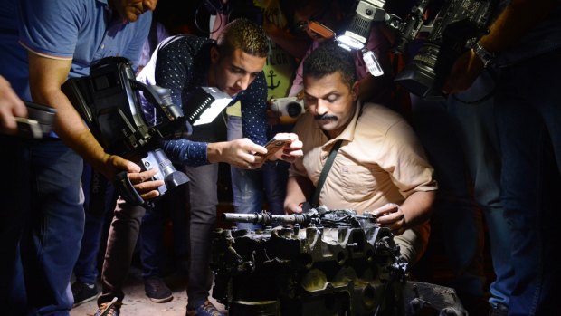 Journalists film and photograph a part from a massive car bomb that exploded in Shubra al-Kheima, Cairo.