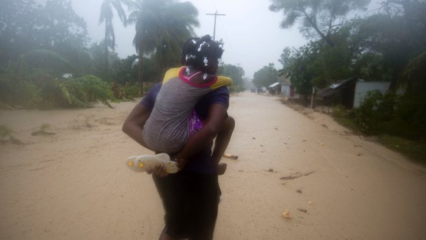 A woman and a child walk in a flooded street as they head to a shelter in the pouring rain caused by Hurricane Matthew in Leogane, Haiti, on Tuesday.