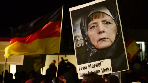 A protester in Dresden in 2015 holds a poster of German Chancellor Angela Merkel, who has been criticised or her migrant-friendly stance, wearing an Islamic headscarf.
