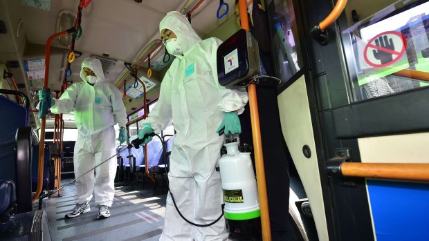South Korean health workers wearing protective gear sanitise a public bus on Sunday.