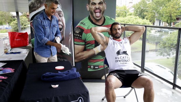 This won't hurt a bit: A Colgate official helps Greg Inglis with his mouthguard fitting at Redfern Oval on Friday. 