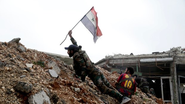 A Syrian army soldier places a Syrian national flag during a battle with rebel fighters  east of Aleppo on December 5.