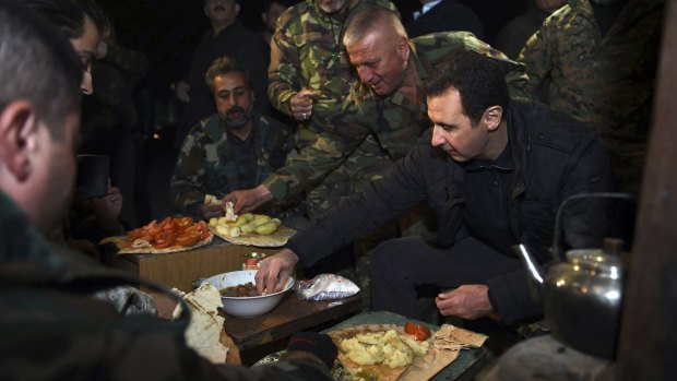 Syrian President Bashar al-Assad eats with soldiers during a visit to Jobar.