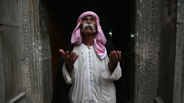 Yazidi elder Sheikh Mirza, 84, last week praying at the entrance to the temple of Lalis, the holiest site of the Yazidi religion in Nineveh Province, Iraq. 
