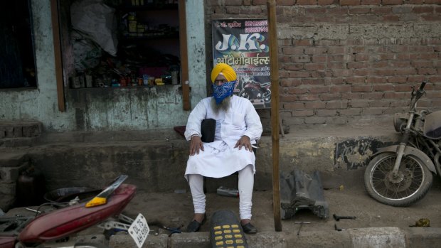 Virdhi, 56, wears a scarf on his face to protect him from pollution, as he sits near a motorcycle workshop in New Delhi last month.