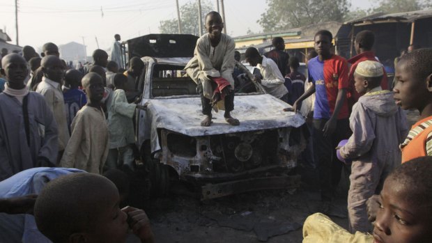 A child stands on a burnt-out police truck following an overnight attack at Sheka police station in Kano, Nigeria, in January 2012. 