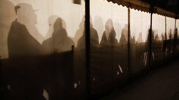 Migrants are silhouetted as they warm themselves inside a waiting tent to get an appointment at the central registration centre for refugees and asylum seekers in Berlin in 2016. 