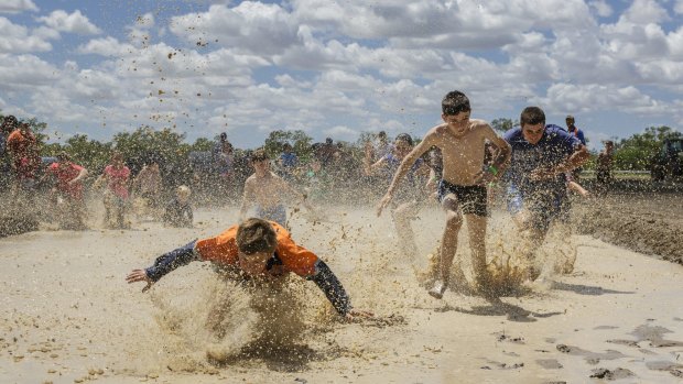 Kids enjoying a race through a mud hole. For many kids in Walgett, recent rains were the first they have experienced.