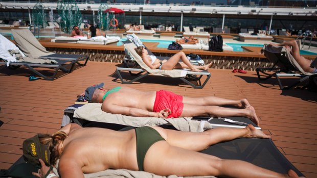 Passengers enjoy the sun by a swimming pool on board the MSC Grandiosa.
