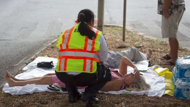 A paramedic checks on a woman, lying on a median strip, after she and others exited the Marco Polo apartment complex.