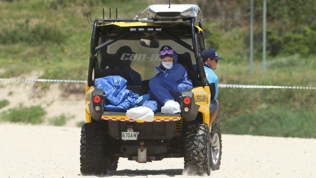Police Forensic Services take the baby's body off the beach.