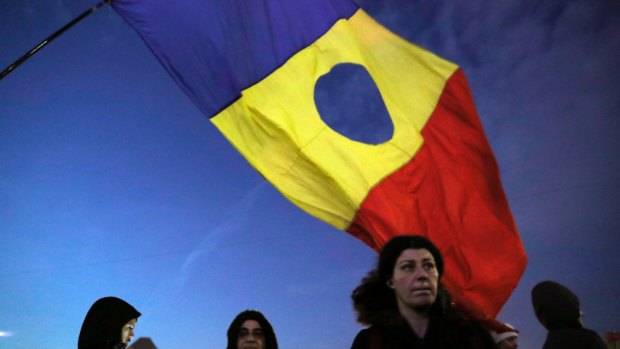 A girl waves a Romanian flag during the protests in Bucharest. During the protests that led to the fall of dictator Nicolae Ceausescu in 1989, protesters frequently waved a Romanian flag with a void at the centre where the communist insignia had been removed.