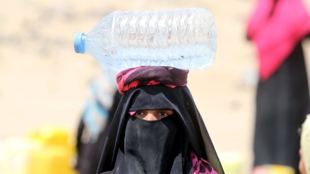 A woman carries precious water in Sanaa.