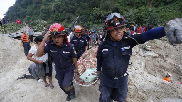 Rescue workers carry a body away from the site of a landslide in Santa Catarina Pinula, on the outskirts of Guatemala City on Friday.