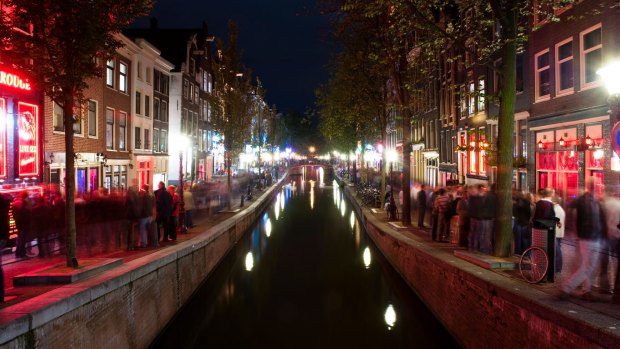The red light district in Amsterdam at night filled with tourists.