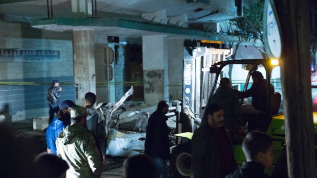Security officers supervise as a forklift moves a car that exploded near the Italian embassy in Tripoli on Saturday.