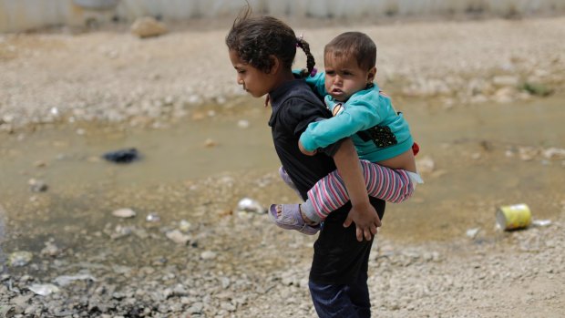 Uncertain future: A Syrian refugee girl holds her brother at the al-Marj camp in Lebanon's Bekaa Valley.  