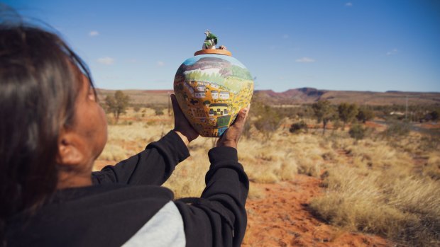 A Hermannsburg Potters artist holding her finished artwork.