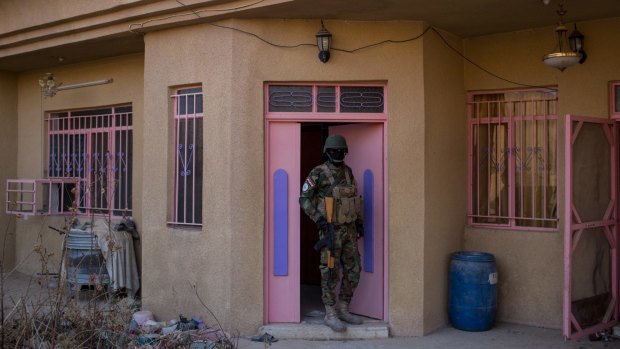 A NPU (Nineveh Plain Protection Units) fighter stands at the front door of a house in Qaraqosh, Iraq, used by IS as a bomb making factory.