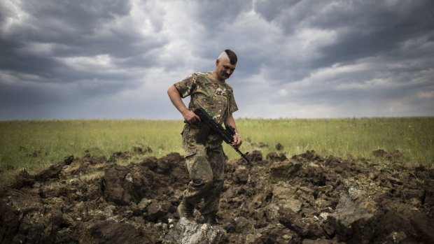 A Ukrainian serviceman investigates the crater left by a Grad rocket in the  Luhansk region in eastern Ukraine, on Monday.
