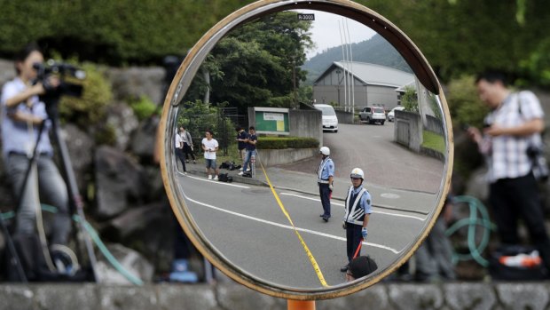 Police officers standing guard are reflected on a road mirror near the Tsukui Yamayuri-en, a facility for the disabled in Sagamihara, outside of Tokyo, Japan, on Tuesday.