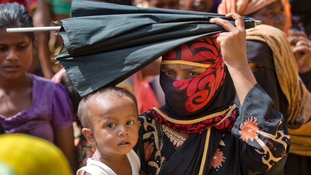 A newly arrived Rohingya woman carries her child while in line to receive food rations in Kutupalong, Bangladesh.