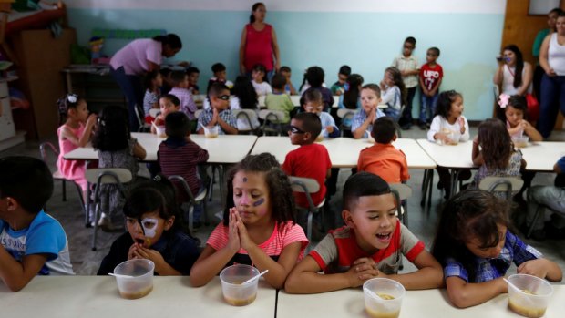 Students pray before a meal of soup cooked for them during an activity for the end of the school year at the Padre Jose Maria Velaz school in Caracas, Venezuela this month.