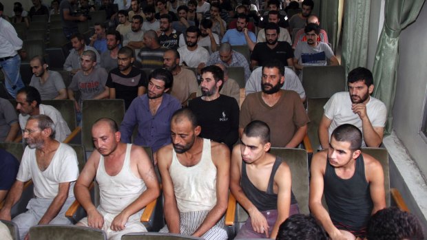 Syrian prisoners sit in a courtroom before their release in Damascus in 2012, while up to 13,000 others have been executed since then. 