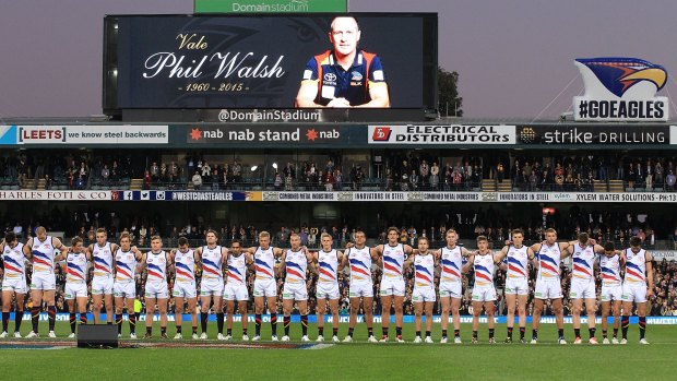 Crows players line up to pay respect to Walsh before a game. 