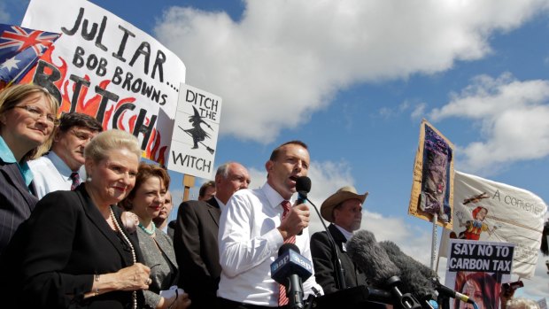 Then opposition leader Tony Abbott in front of a "ditch the witch" poster at a rally outside Parliament House in 2011.