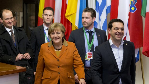 Greek Prime Minister Alexis Tsipras, right, walks with German Chancellor Angela Merkel, centre, as they leave an EU summit in Brussels on Tuesday.