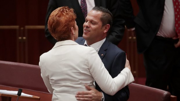 Senator Pauline Hanson embraces Senator Peter Georgiou after he delivered his first speech to the Senate on Wednesday.