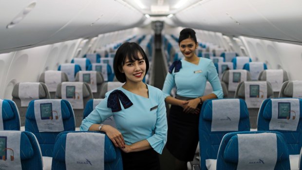 Stewardesses pose in the economy cabin of SilkAir's new Boeing 737 Max 8 aircraft.