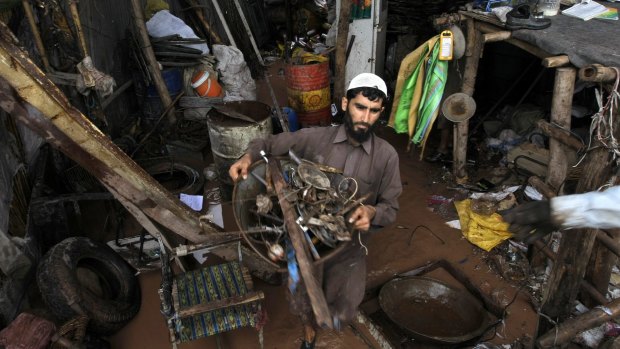 A Pakistani villager salvages belongings from his flooded house.