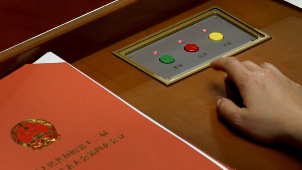 A delegate prepares to press buttons to vote on the draft resolutions during the closing session of the annual National People's Congress.